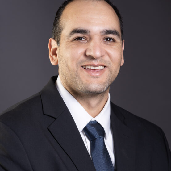 "Mario Galvan is a insurance professional, this is headshot portrait of him smiling in suit".